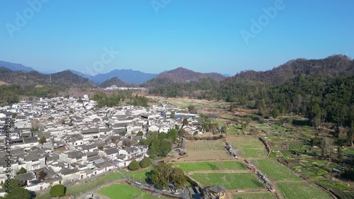 Xidi, China: Aerial drone footage of the famous Xidi ancient village surrounded by field in the mountain countyside near Huangshan in Anhui province in China on a sunny winter day. 