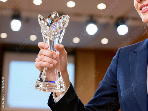 Close-up of a businesswoman holding a beautiful flower-shaped crystal trophy in an office seminar room, representing professional achievement, female leadership, and corporate success