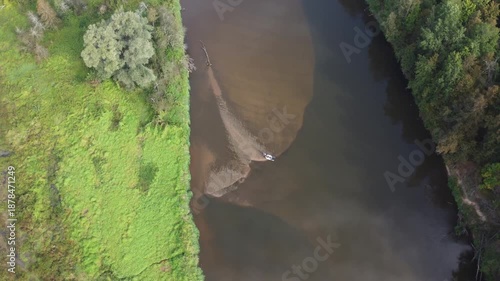 The drying up of the forest river is caused by an anthropogenic factor. River shallowing. Flying over a forest river, a boat in the middle of the river on a sandbar. High quality 4k footage
