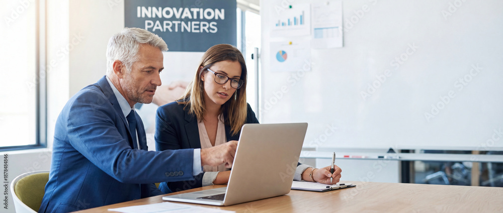 Fototapeta premium Two professional business people working together. Partners mature man and woman discussing project in office. Team leader explain trainee working process using tablet pc computer. Banner, copy space