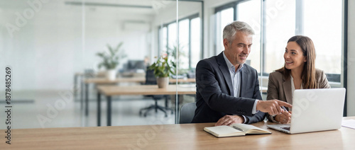 Two professional business people working together. Partners mature man and woman discussing project in office. Team leader explain trainee working process using tablet pc computer. Banner, copy space