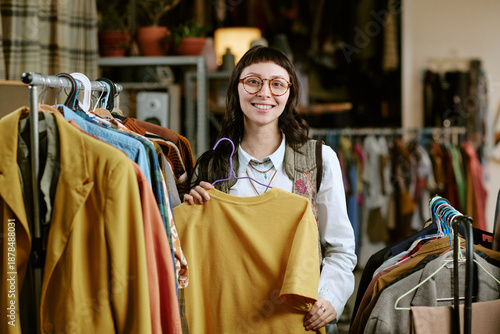 Bild auf Leinwand Portrait of young adult biracial woman smiling while holding second hand shirt o