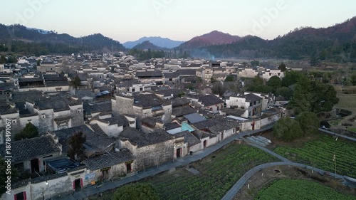 Xidi, China: Aerial backward drone footage of the facade of houses with Hui architecture in the Xidi ancient village surrounded by field in the hills near in Anhui province in China. 