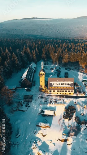 See the Kralovka lookout tower sitting in the Jizera Mountains during winter. Explore the snowy landscape and observe the surrounding nature and buildings.