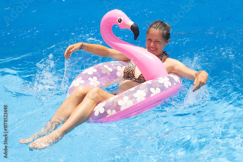 Summer pool lifestyle with woman on pink flamingo inflatable