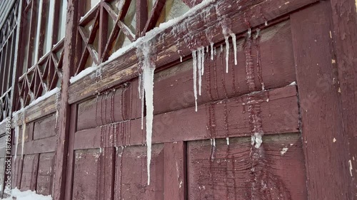Icicles in winter on an antique wooden window with patterns close-up as a background