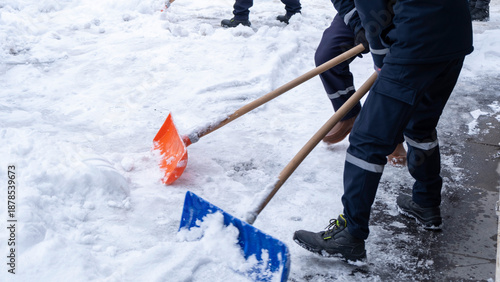 Municipal workers are cleaning the sidewalks blocked by snow. snow removal workers with snow shovels