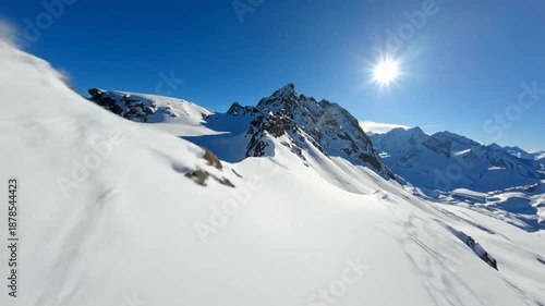 Stunning Snowy Mountain Ridge Under Bright Blue Sky and Sun.