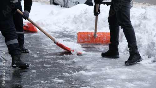 Municipal workers are cleaning the sidewalks blocked by snow. snow removal workers with snow shovels