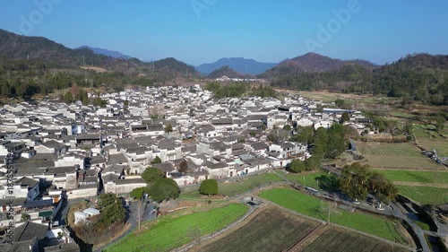 Xidi, China: Aerial drone footage of the famous Xidi ancient village surrounded by field in the mountain countyside near Huangshan in Anhui province in China on a sunny winter day. 