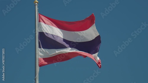 Close-up of the tricolor Thai flag blowing in the breeze, showcasing red, white, and blue stripes of Thailand