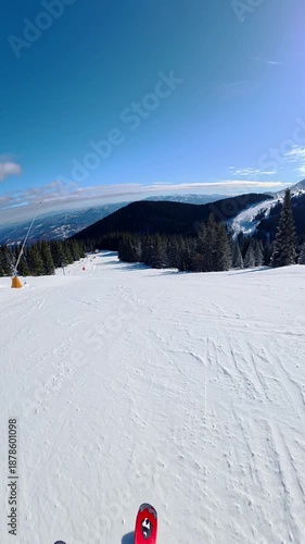 Beautiful POV ski landscape on the mountains. Skier skis down a snowy mountain trail in sunny weather.
