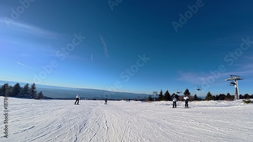 Beautiful POV ski landscape on the mountains. Skier skis down a snowy mountain trail in sunny weather.