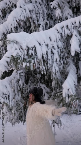 Woman plays with snow under tree in winter wonderland during daytime