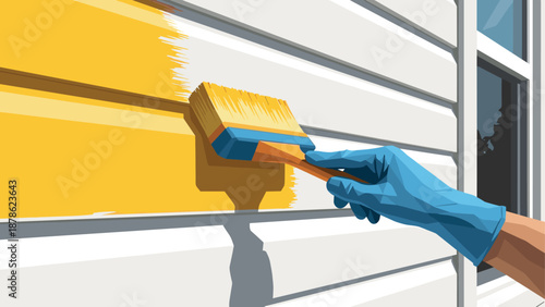 Hand in glove painting yellow wall with brush on sunny day