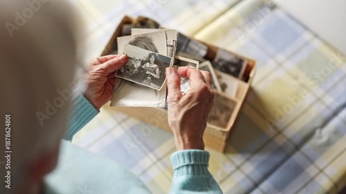 Senior woman looking through old photos from the past, close-up on her hands
