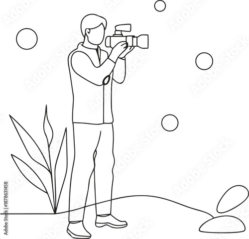 Man holding video camera standing on ground with plant
