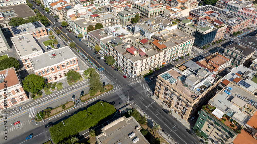 Fototapeta premium Wide aerial view of a historic city center. Densely packed buildings with classic architecture are intersected by a long, straight main road. It is located in Messina, Sicily, Southern Italy.