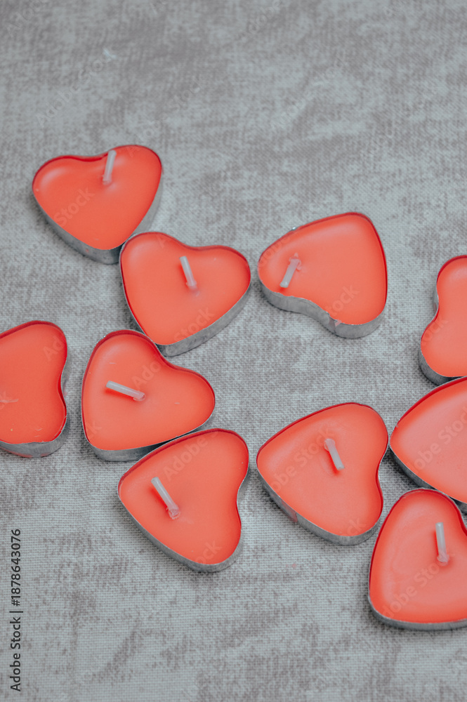 Fototapeta premium red heart-shaped candles arranged together on neutral background. Love, romance, Valentine’s Day, wedding decor, relationship, celebration and romantic lifestyle concept.