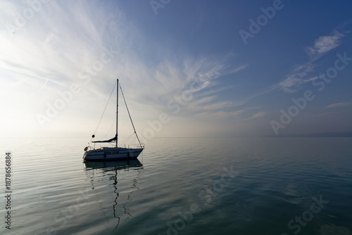 Tableau sur toile Sailing boat floats on calm water in Hungary during early morning light near a q