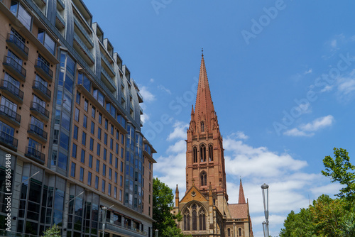 Wallpaper Mural Striking Urban Architecture: A Modern High-Rise and Historic Neo-Gothic Church Spire Rise Against a Bright Blue Sky Torontodigital.ca