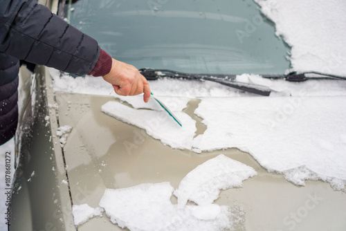 Wallpaper Mural cleaning an ice-covered car from snow and ice hand with a scraper removing ice crust from a car hood concept of winter car maintenance and cold weather difficulties Torontodigital.ca