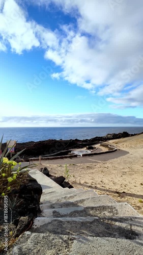 Scenic view of the Atlantic Ocean from Charco del Palo, a nudist resort in Lanzarote featuring natural pools formed by lava, under a beautiful blue sky with scattered clouds on a sunny day
