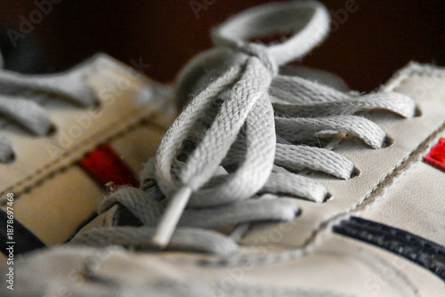 Extreme close-up of white cotton shoelaces tied in a bow on a leather sneaker