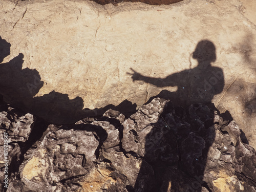 Foto Shadow of a woman cast on stone ground beside a waterfall, creating a quiet and contemplative nature scene