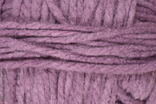 A macro shot shows the detailed texture of a soft purple wool yarn ball with thick intertwined threads filling the entire frame