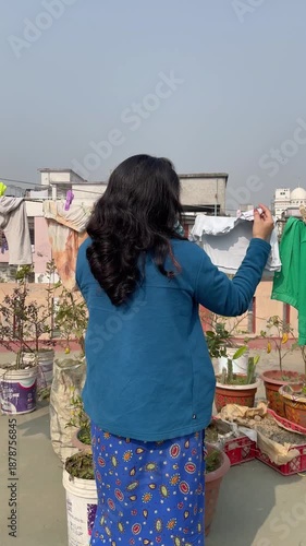 Bangladeshi woman hanging clothes on a rooftop clothesline to dry under the sun in Dhaka, Bangladesh, capturing everyday urban life and local lifestyle.