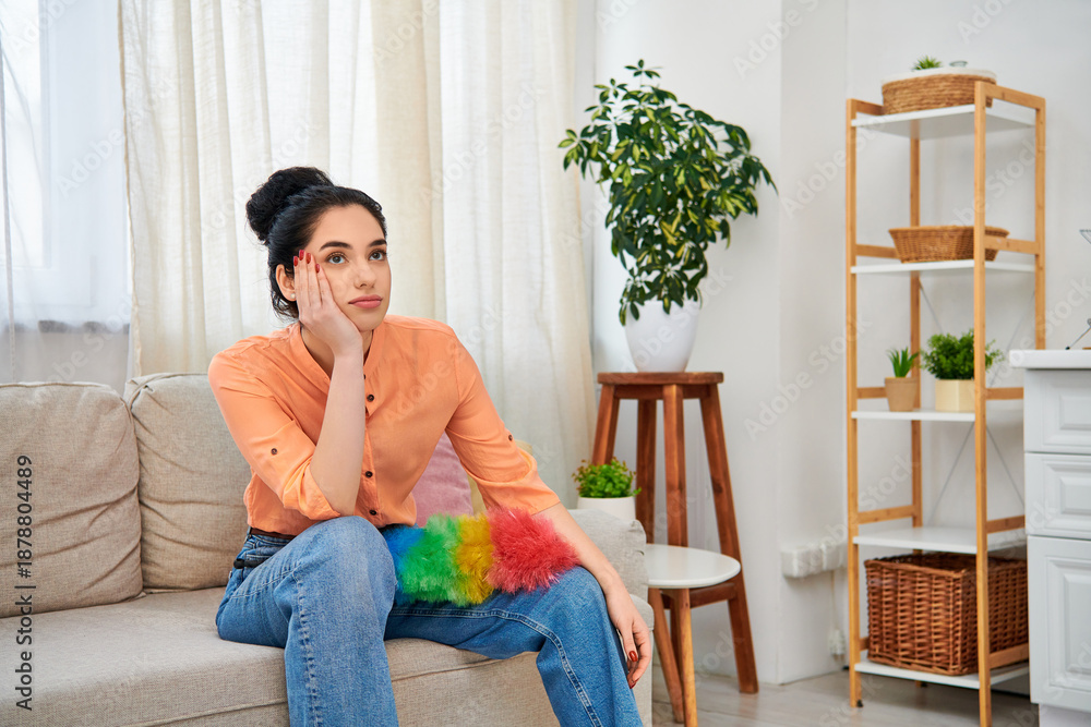 Obraz premium Young woman enjoying a moment of pause while cleaning her modern apartment