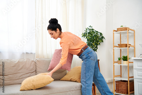Tableau sur toile A young woman happily arranges cushions on her sofa, embracing the joy of home c