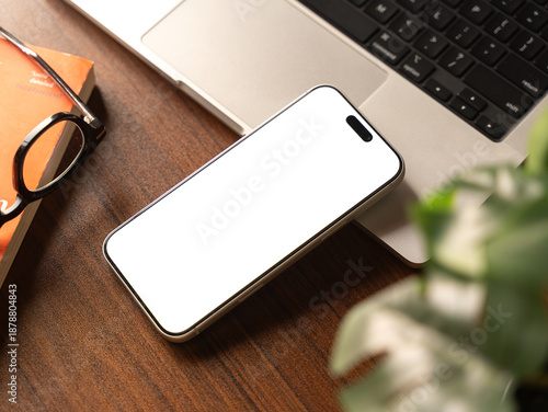 Real mobile phone mockup on wooden desk setup. Isolated cellphone template