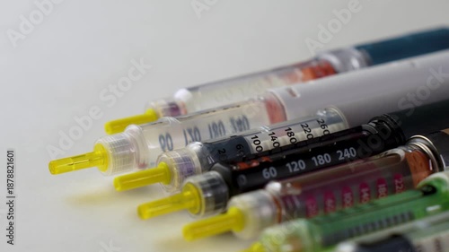 Close-up of diabetic insulin pens and syringes with measurement scale on a light background. Medical devices used for insulin injection and diabetes management