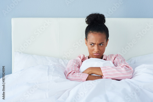Grumpy, woman and wake up in bedroom for morning, frustrated and tired or fatigue in home. Insomnia, female person and angry or moody in apartment with blanket, pillow and unhappy for mock up space