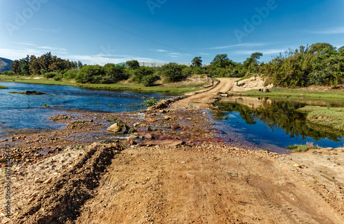 Rough gravel road with washed out causeway over the Gamtoos River near Hankey in the Eastern Cape, South Africa