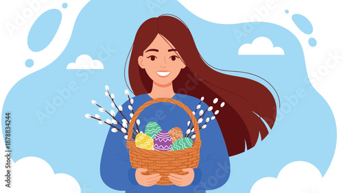 Happy young woman holding a wicker basket full of colorful decorated Easter eggs and pussy willow branches, celebrating the spring holiday.
