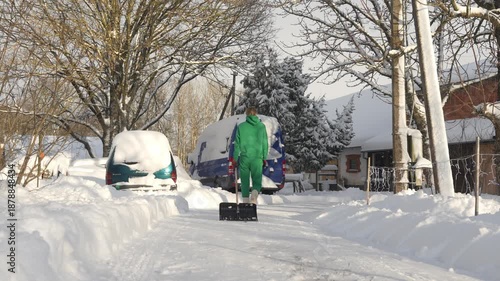 Slow motion camera shot of young woman walking back to the house after shoveling snow from the driveway. Strong, independent female working outside in the winter.