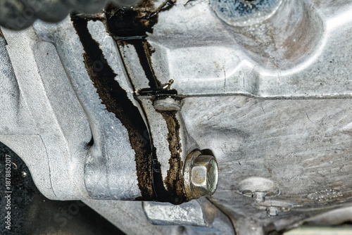 Black oil leaking from the rear engine oil seal between the engine and gearbox on a vehicle