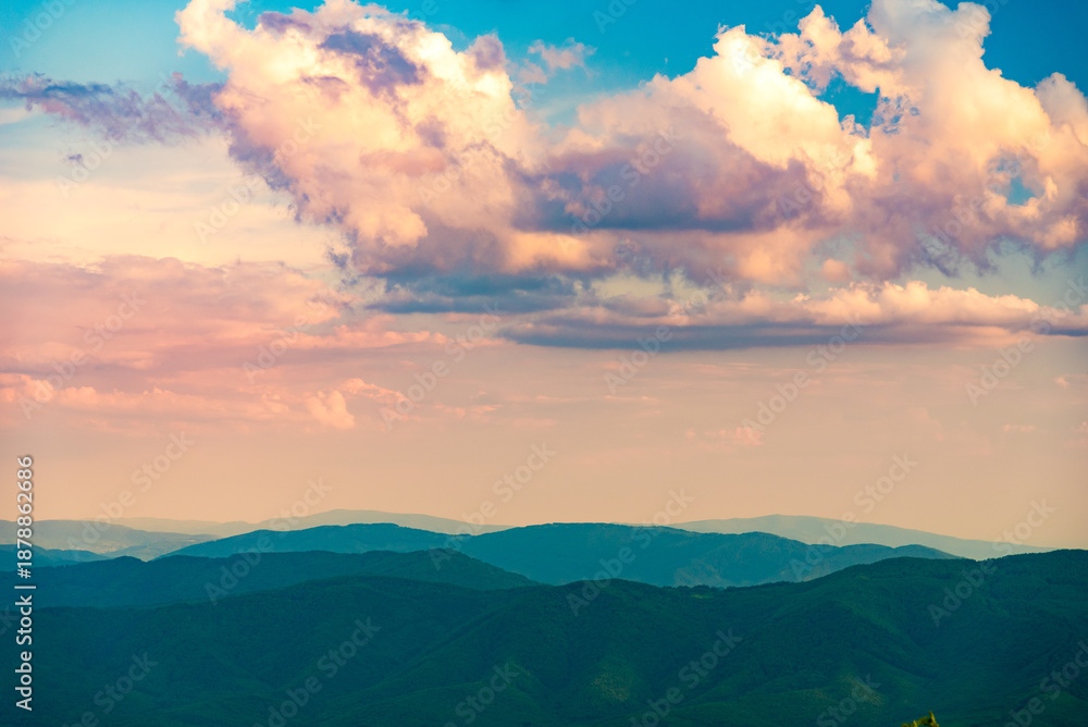 Fototapeta premium Sunset over layered mountain ridges in the Bieszczady Mountains, seen from Wielka Rawka and Mała Rawka viewpoints. Peaceful nature landscape with dramatic sky and soft evening light. 