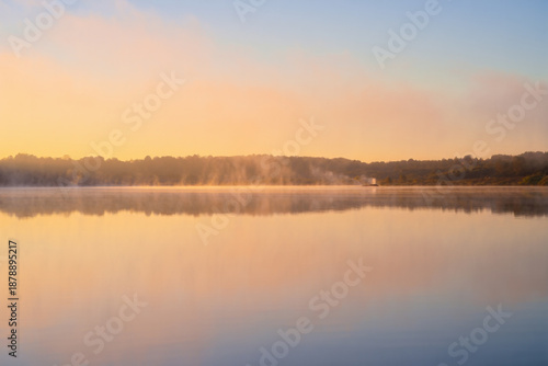 Wallpaper Mural a serene landscape features a calm lake reflecting the warm glow of a golden sunrise over forested hills high quality professional detailed modern elegant stylish clean Torontodigital.ca