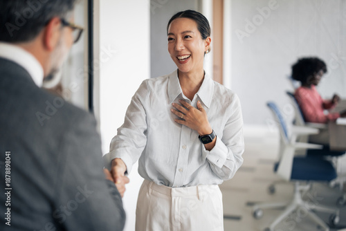Obraz na plátně Businesswoman greeting coworker with a handshake in office