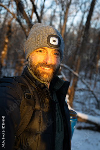 Bearded man taking a selfie in the sunset in the woods