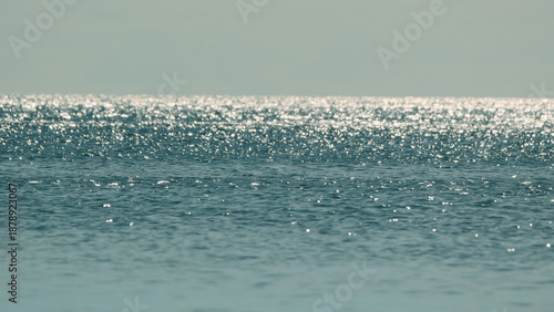 Tranquil sea with sun glare and sparkling reflections on the water surface