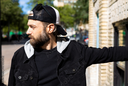 Bearded man leaning against wall in city 