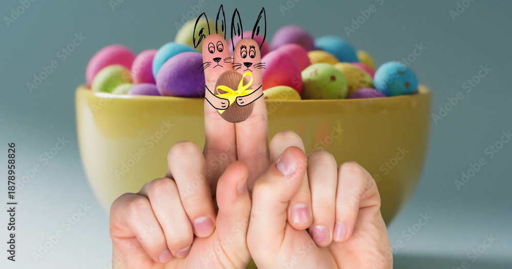 Fototapeta premium Image of fingers with easter bunnies and easter egg over bowl of easter eggs on blue background