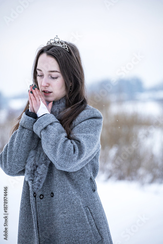 Snow Queen. A young girl in a white dress in the snow. Girl in a white dress. Bride. Winter cold weather. Model. Young woman in winter park.