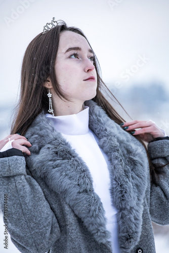 Snow Queen. A young girl in a white dress in the snow. Girl in a white dress. Bride. Winter cold weather. Model. Young woman in winter park.