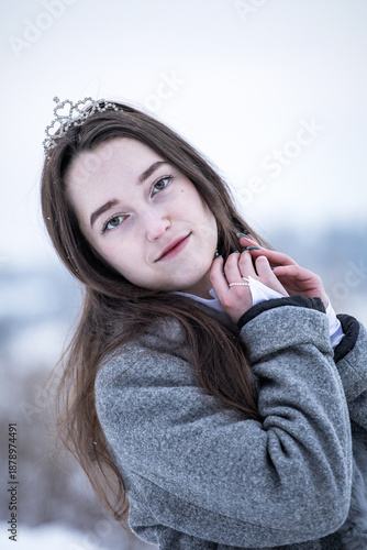 Snow Queen. A young girl in a white dress in the snow. Girl in a white dress. Bride. Winter cold weather. Model. Young woman in winter park.